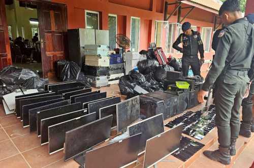 This pool photo taken on July 17, 2025 and released on July 18 by Agence Kampuchea Presse (AKP) shows military police looking at computers, smartphones and other equipment seized during a raid on a scam centre in Kandal province.