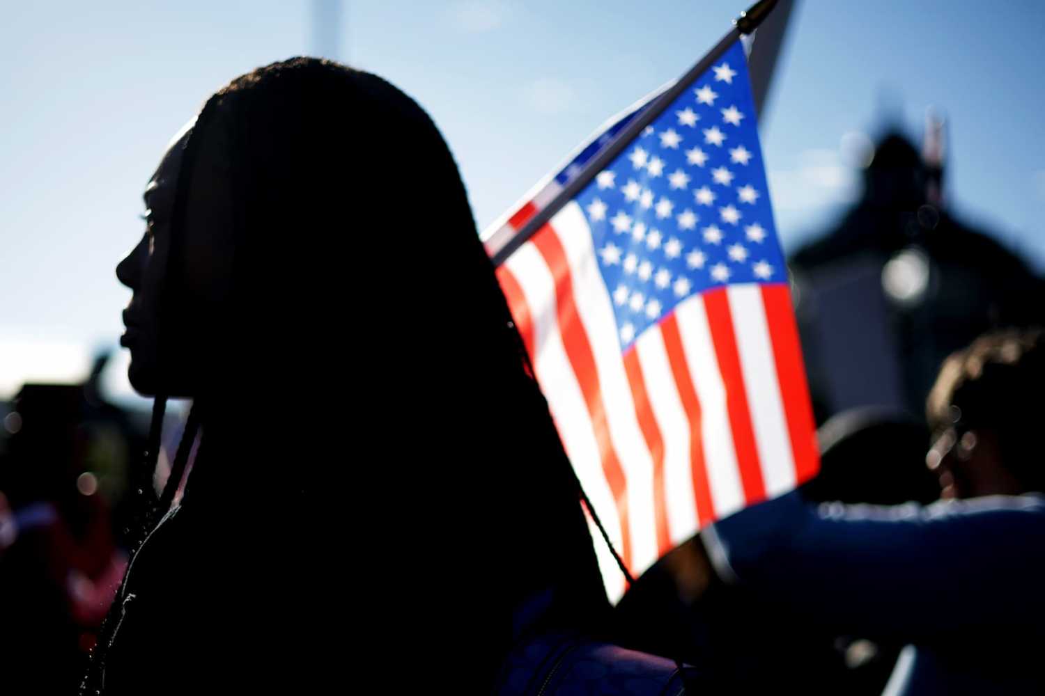 WASHINGTON, DC - OCTOBER 15: An activist holds a U.S. flag during a rally in front of the U.S. Supreme Court on Oct. 15, 2025. The Supreme Court heard oral arguments that day in Louisiana v. Callais, a major case concerning a congressional map that created a second majority-Black district in Louisiana.