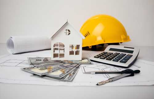 Yellow helmet, money and model of house on drawings
