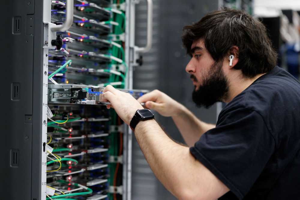 A man pulls a shelf out of a server rack