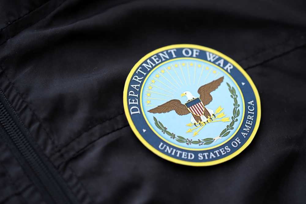 US Department of War badge on black uniform fabric surface close up.