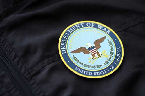 US Department of War badge on black uniform fabric surface close up.