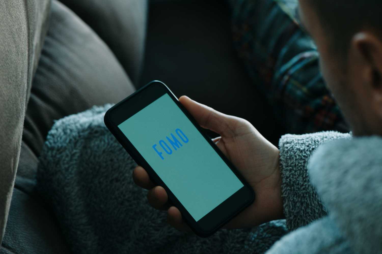 Person using cellphone that says FOMO