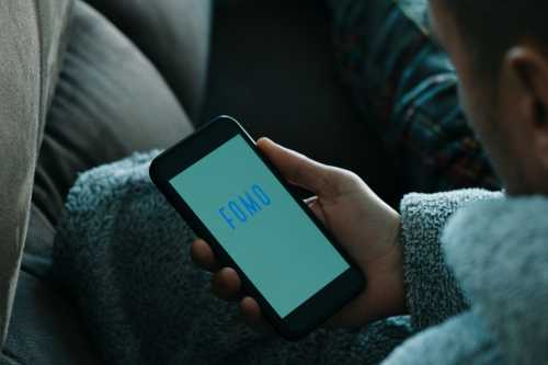 Person using cellphone that says FOMO
