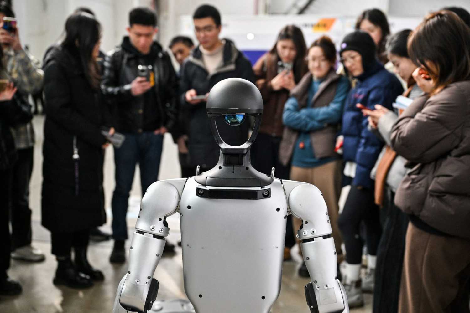 People stand next to a humanoid robot from Unitree Robotics during the Global Developer Conference, organized by the Shanghai AI Industry Association, in Shanghai on February 21, 2025.