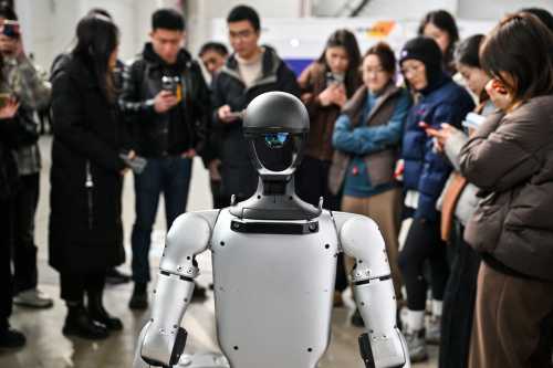 People stand next to a humanoid robot from Unitree Robotics during the Global Developer Conference, organized by the Shanghai AI Industry Association, in Shanghai on February 21, 2025.