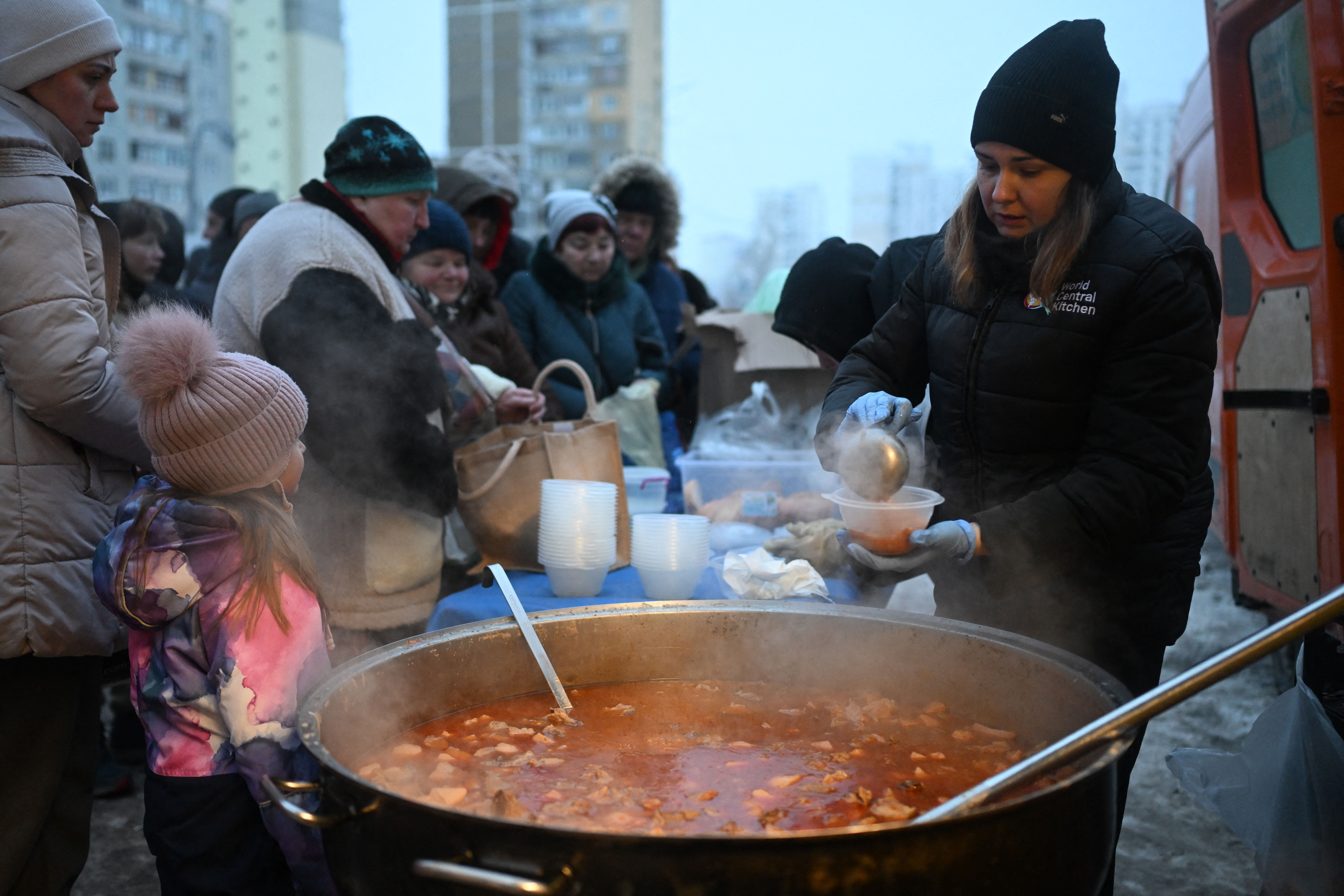 Volunteers of the US-based food charity World Central Kitchen distribute hot meal to local residents in a residential area of Kyiv that has been left without electricity and water due to recent Russian strikes battering the energy sector on January 22, 2026, amid the Russian invasion of Ukraine.