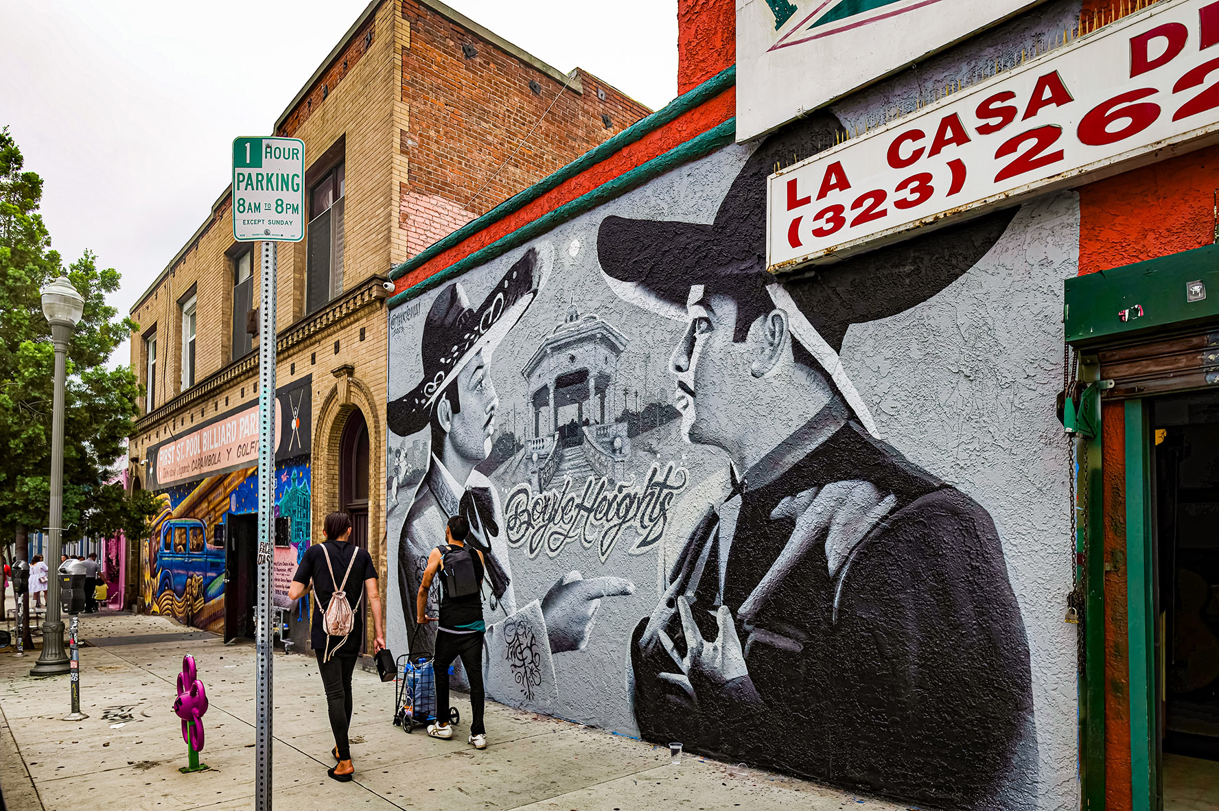 EAST LOS ANGELES, CA, U.S.A. - SEPT. 2, 2023: Photo of two men walking past businesses with painted facades on First Street in Boyle Heights, the heart of Chicano Los Angeles.