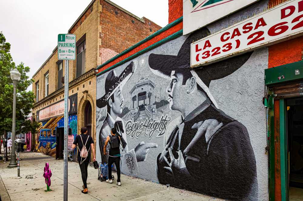 EAST LOS ANGELES, CA, U.S.A. - SEPT. 2, 2023: Photo of two men walking past businesses with painted facades on First Street in Boyle Heights, the heart of Chicano Los Angeles.