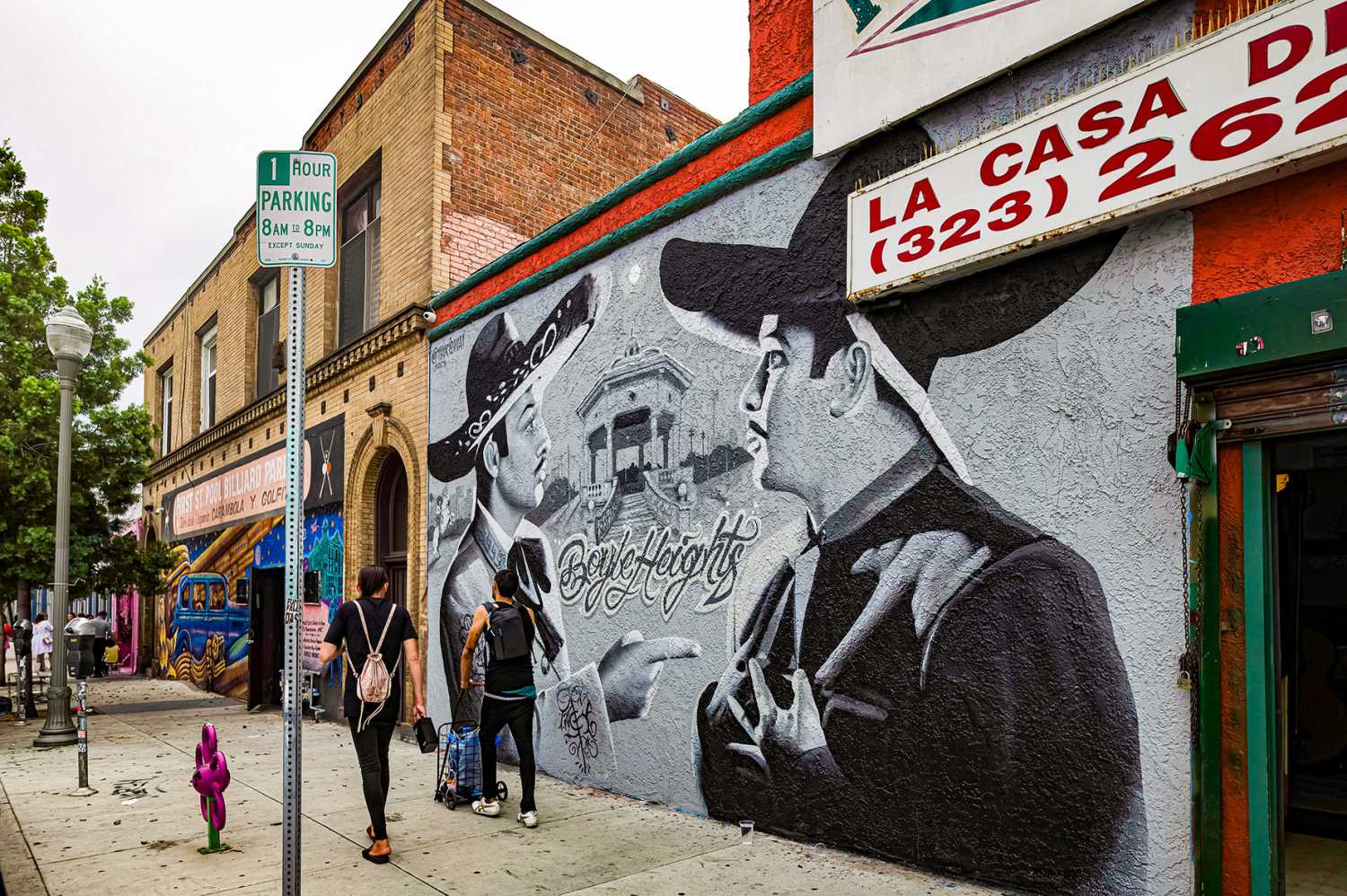 EAST LOS ANGELES, CA, U.S.A. - SEPT. 2, 2023: Photo of two men walking past businesses with painted facades on First Street in Boyle Heights, the heart of Chicano Los Angeles.