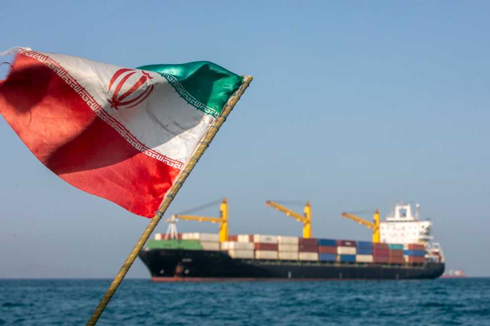 An Iranian flag flutters in the wind as ships remain anchored on May 16, 2026 in the Strait of Hormuz near Larak Island, Iran
