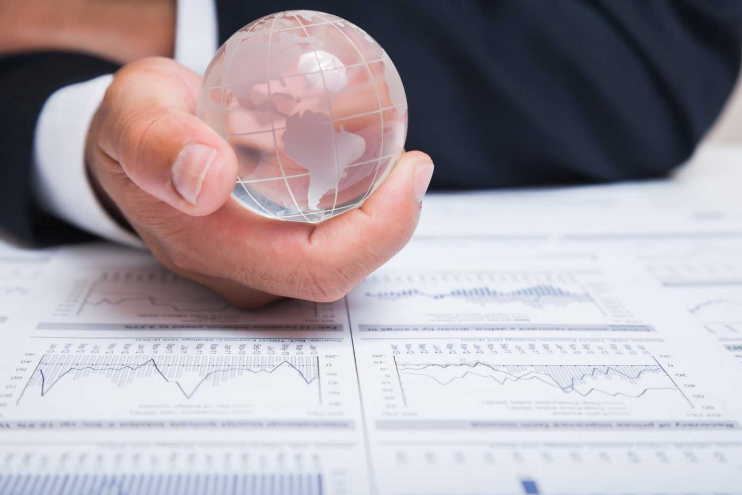 Businessman holding glass globe with charts on papers