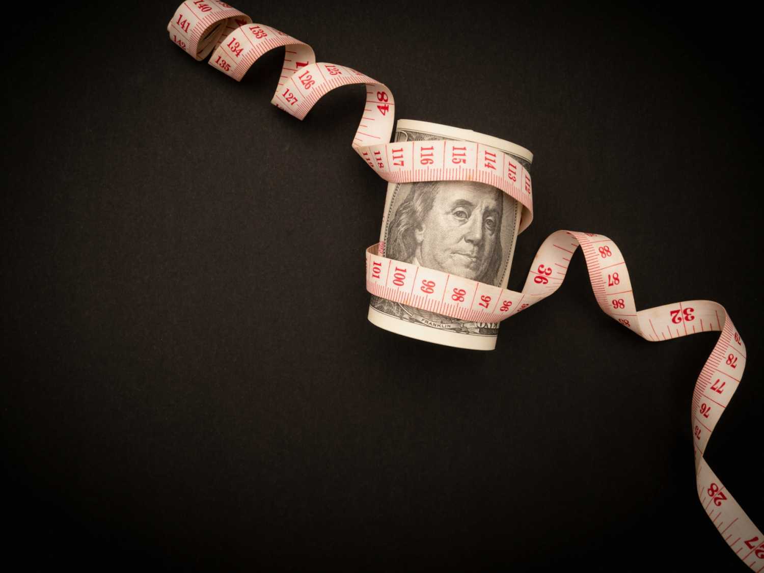 Tape measure wrapped around a US dollar banknote