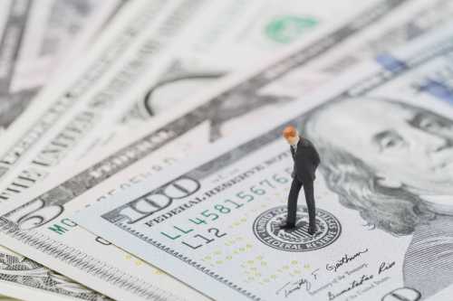 Miniature businessman standing on money