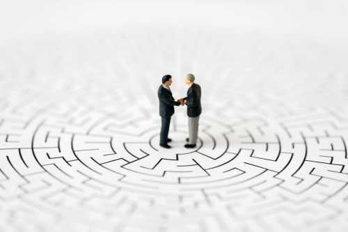 Miniature business people shake hands
