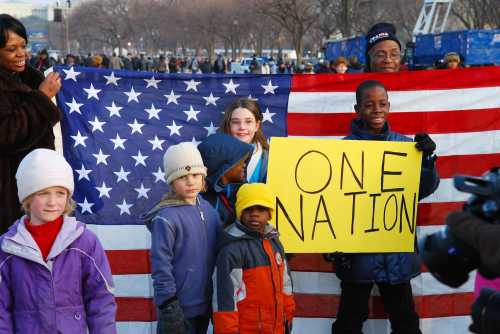 Children stand with the American flag and a sign that reads "one nation" on the eve of the inauguration of Barack Obama in January 2009.