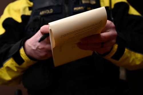Portland Police officer Eli Arnold writes a ticket for smoking drugs in public during a patrol on a bicycle in downtown Portland, Oregon on January 25, 2024.