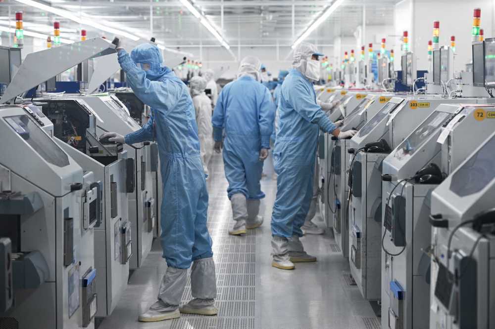 Technicians work on chip processing equipment at a semiconductor manufacturing plant in Suqian, in eastern China's Jiangsu province on October 20, 2025.