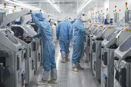 Technicians work on chip processing equipment at a semiconductor manufacturing plant in Suqian, in eastern China's Jiangsu province on October 20, 2025.