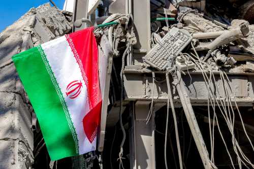 An Iranian national flag is placed by the rubble of a collapsed building following strikes at Sharif University of Technology in Tehran on April 7, 2026.