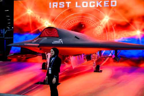 A woman poses in front of an Anka-3, Turkey's first flying-wing, deep-strike stealth unmanned fighter jet, manufactured by Turkish Aerospace Industries (TUSAS) during the opening day of the SAHA EXPO 2024, an International Defence and Aerospace exhibition, in Istanbul on May 5, 2026.