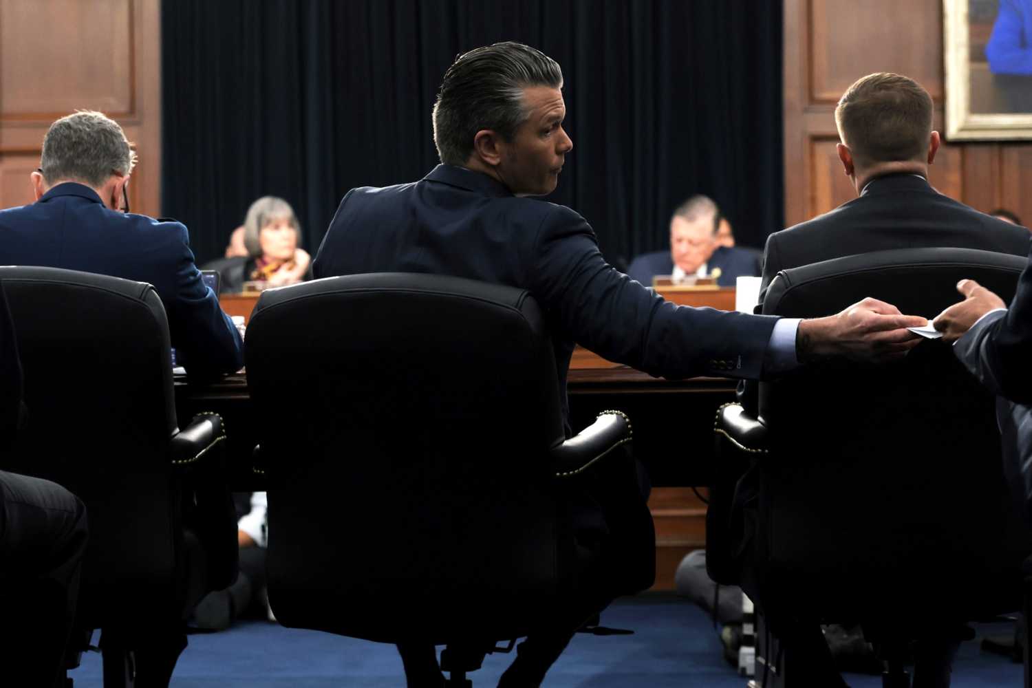 U.S. Secretary of War Pete Hegseth (C) hands an aide a note as he testifies during a House Committee on Appropriations, Subcommittee on Defense hearing in the Rayburn House Office Building on May 12, 2026 in Washington, DC.