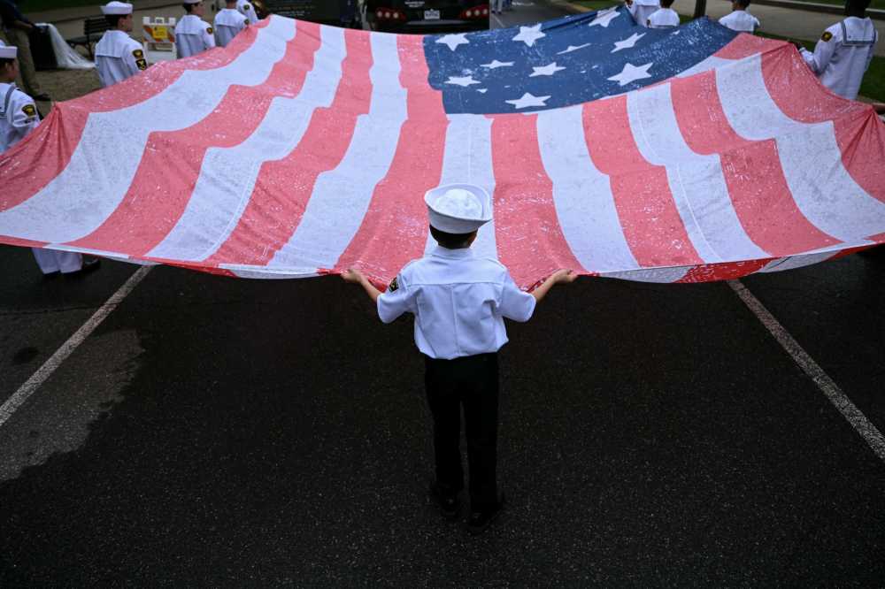 A young boy helps carry a large American flag during the National Memorial Day Parade on Constitution Avenue in Washington, DC, May 25, 2026.