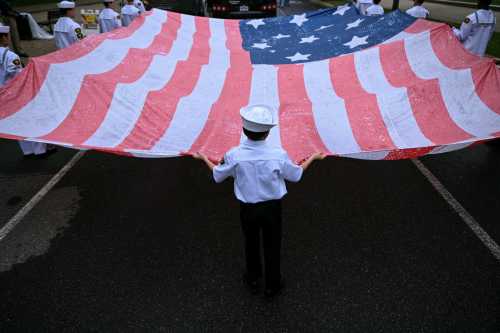 A young boy helps carry a large American flag during the National Memorial Day Parade on Constitution Avenue in Washington, DC, May 25, 2026.