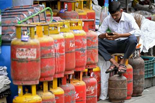 A man uses a mobile phone next to liquefied petroleum gas (LPG) cylinders outside a shop in Bengaluru on June 2, 2026 amid global energy crisis triggered by the Middle East war.