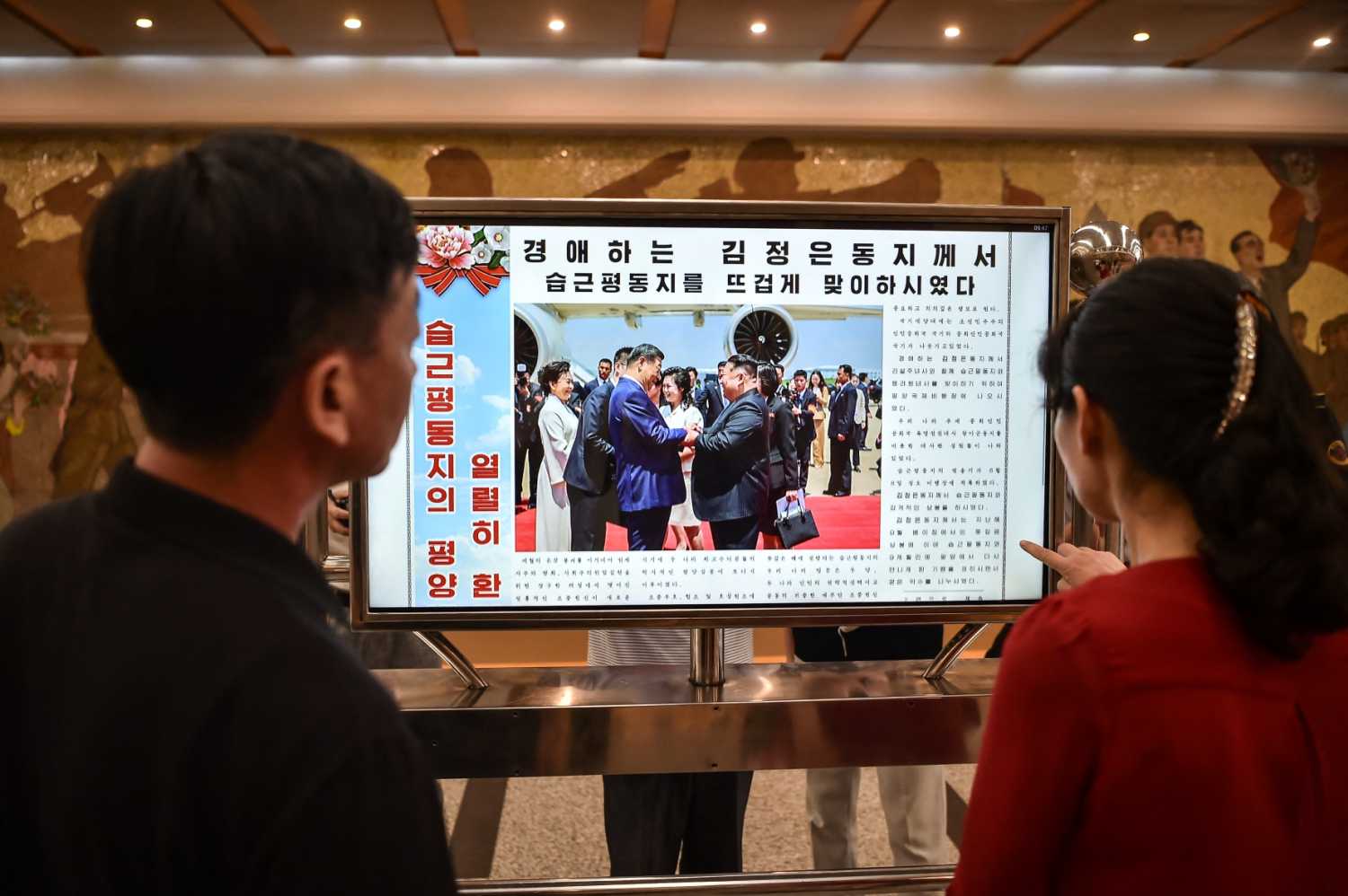 People look at a screen with the newspaper "Rodongsinmun" showing the news on the visit of China's President Xi Jinping, in the Kaeson Station of the Pyongyang Metro in Pyongyang on June 9, 2026.