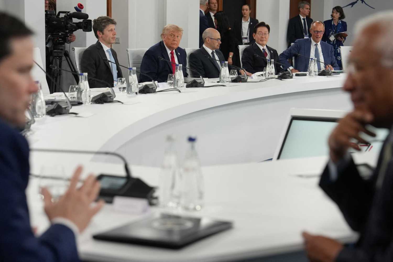 U.S. President Donald Trump reacts next to Open AI CEO Sam Altman and Google DeepMind CEO Demis Hassabis, South Korean President Lee Jae Myung, and Germany's Chancellor Friedrich Merz as U.S. Secretary of State Marco Rubio (L) and European Council President Antonio Costa (R) talk in the foreground during a working lunch meeting of G7 members, partner countries, and artificial intelligence business leaders as part of the G7 summit, in Evian, eastern France, on June 17, 2026.