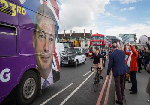 A cyclist sticks his middle finger up at a picture of U.K. Independence Party Leader Nigel Farage on the side of a campaign bus on Westminster Bridge during a 'Fishing for Leave' flotilla along the Thames River on June 15, 2016 in London, England.