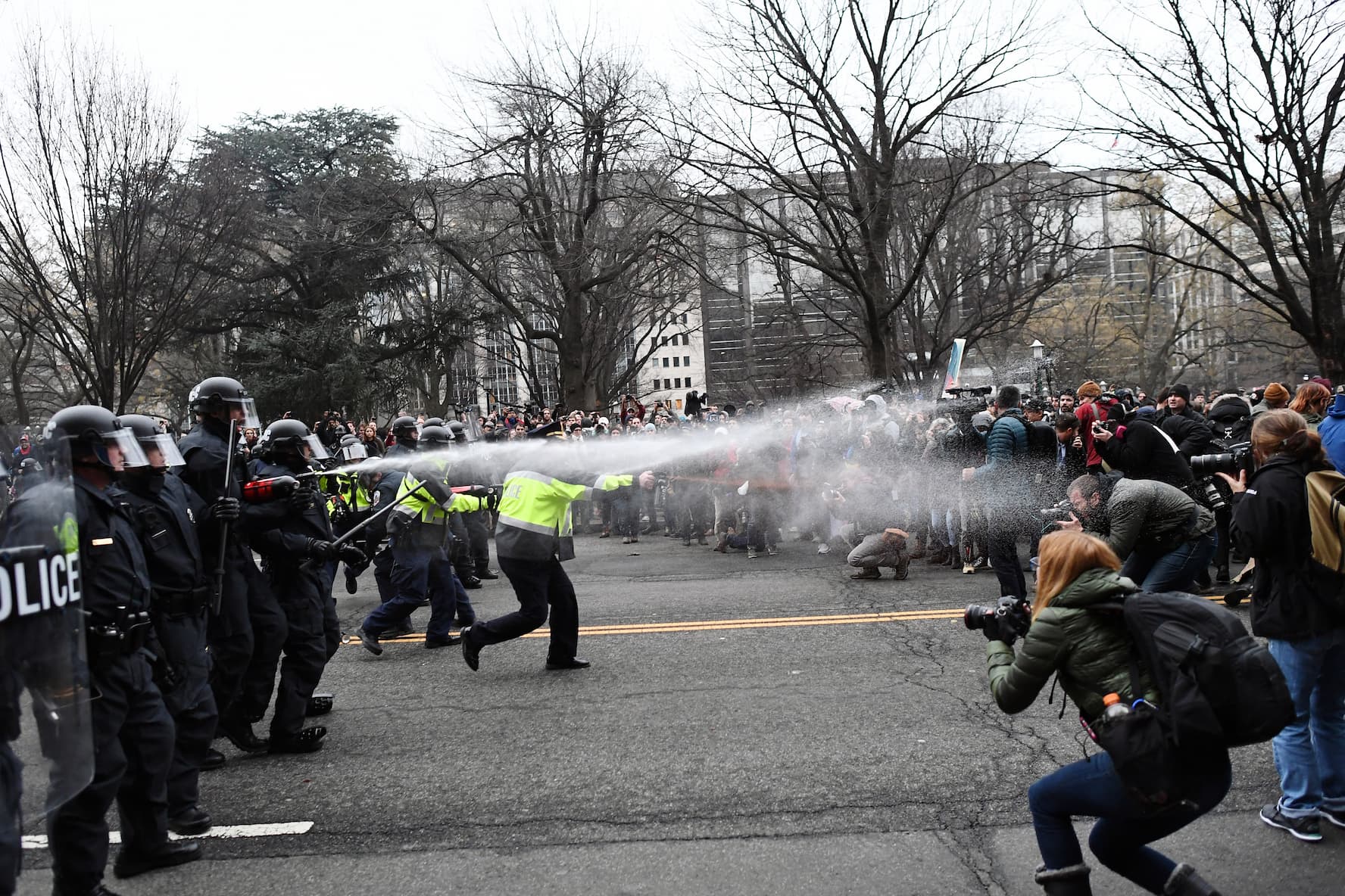TOPSHOT - Police pepper spray at anti-Trump protesters during clashes in Washington, D.C., on January 20, 2017.