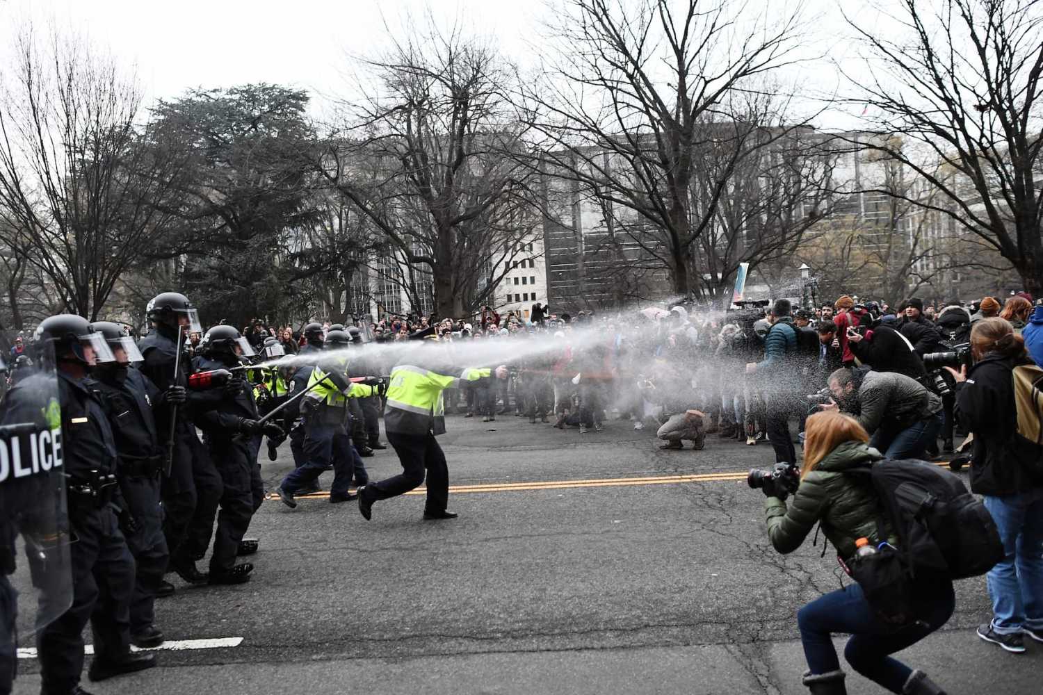 TOPSHOT - Police pepper spray at anti-Trump protesters during clashes in Washington, D.C., on January 20, 2017.