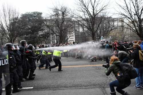 TOPSHOT - Police pepper spray at anti-Trump protesters during clashes in Washington, D.C., on January 20, 2017.