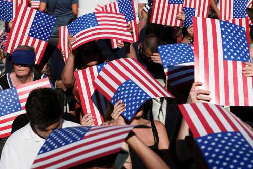People hold U.S. flags ahead of a rally kicking off the Great American State Fair marking the 250th anniversary of U.S. independence on the National Mall in Washington, D.C.