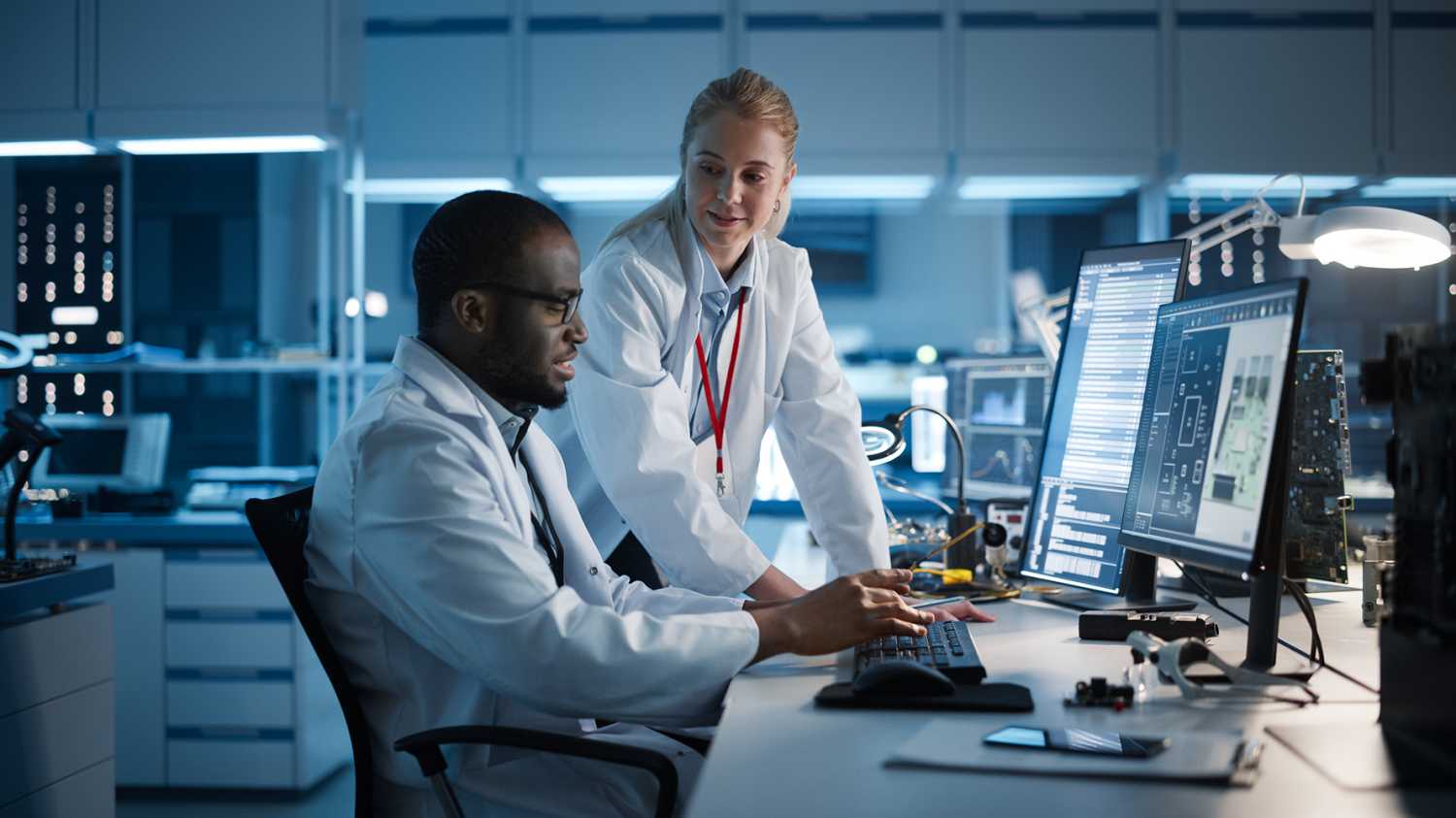 Female Engineer Project Manager Talks With Chief Engineer working on Computer.