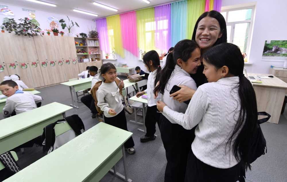 A teacher hugs her young students in the classroom