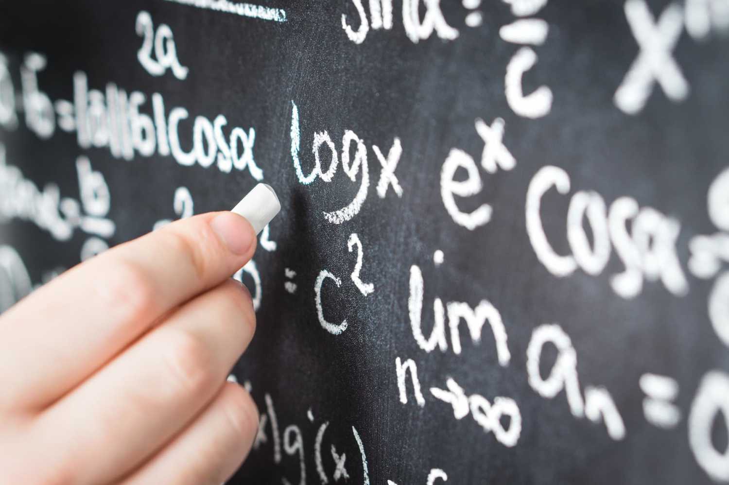 Professor writing mathematical formula and equation to blackboard in school classroom.