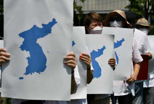 South Korean pro-unification protesters hold placards showing the Korean Peninsula during a demonstration in celebrations to mark the 20th anniversary of the historic June 2000 inter-Korean summit and joint peace declaration between South Korea's President Kim Dae-jung and North Korea's leader Kim Jong Il, in Seoul on June 13, 2020.