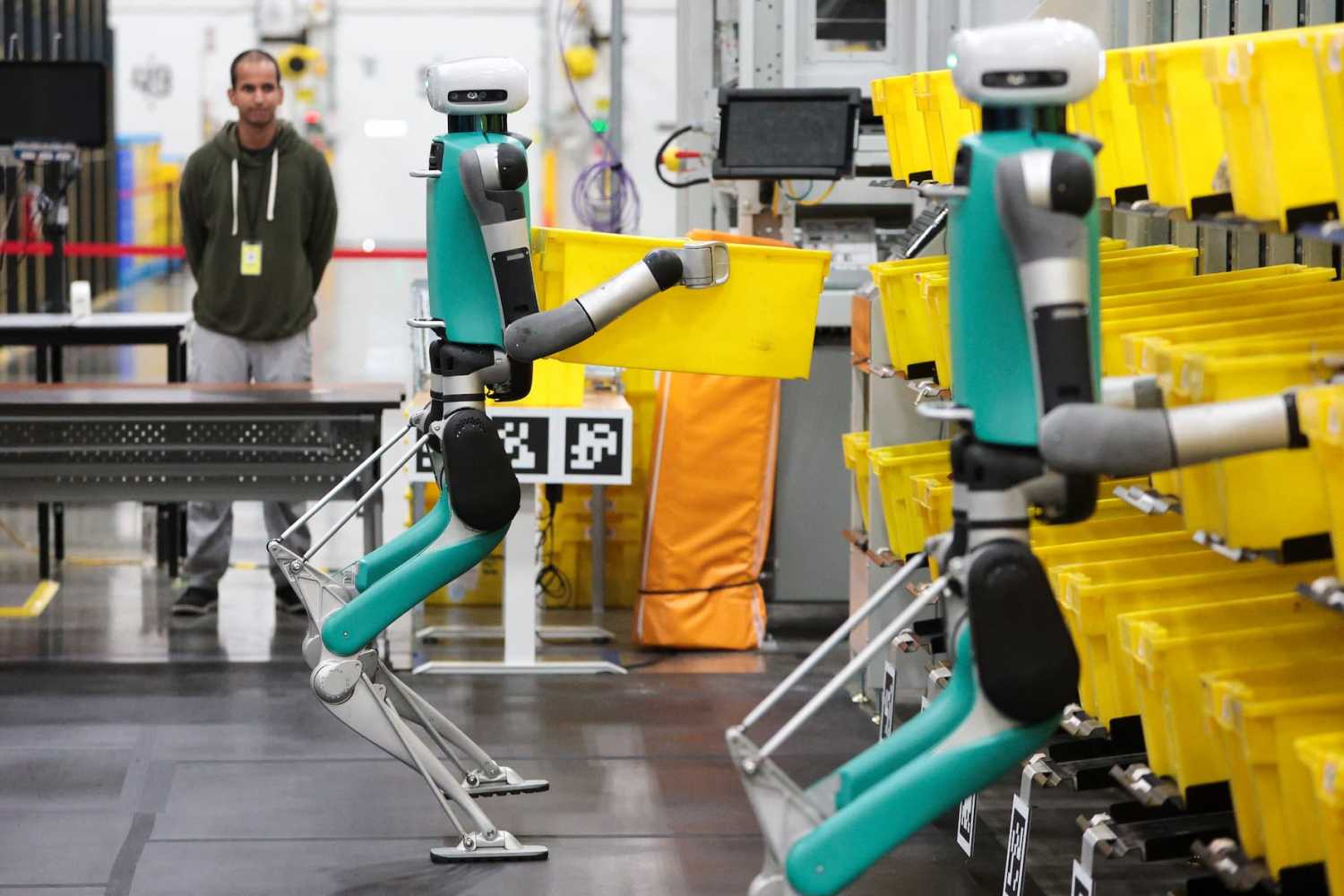 TOPSHOT - Bipedal robots in testing phase move containers during a mobile-manipulation demonstration at Amazon's "Delivering the Future" event at the company's BFI1 Fulfillment Center, Robotics Research and Development Hub in Sumner, Washington, on Oct. 18, 2023.