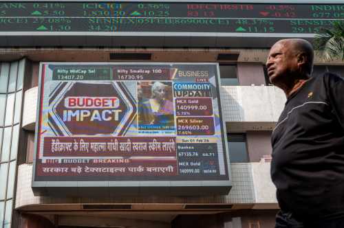 A pedestrian walks past a digital screen displaying a broadcast of the budget speech by Indian Finance Minister Nirmala Sitharaman at the Bombay Stock Exchange (BSE) in Mumbai on February 1, 2026.
