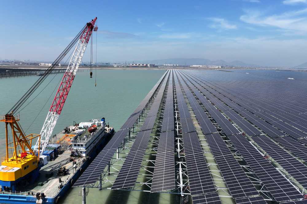 Workers install solar panels with a crane at the CNNC Tianwan tidal flat photovoltaic power plant in Lianyungang, in China's eastern Jiangsu province, on April 19, 2026.