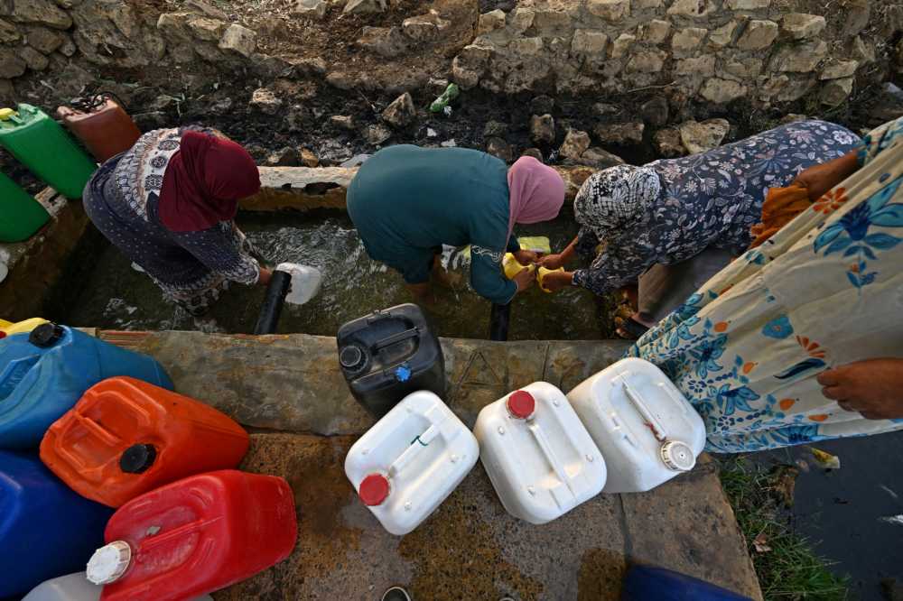 Women fetch water from a natural spring on a hot day in the mountains of Bizerte on July 21, 2026. Tunisia has been experiencing a heatwave for a week, with temperatures exceeding 48 degrees celsius as people endure the ordeal of daily water and electricity cuts.