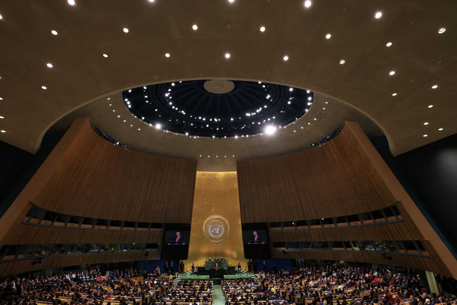 Wide view of the General Assembly Hall at the United Nations with seats filled while President Trump delivers remarks at the podium