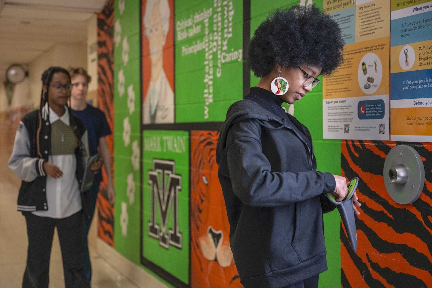An eighth grader unlocks her cellphone pouch after school followed by other students at Mark Twain Middle School in Alexandria, Virginia, on March 6, 2025.