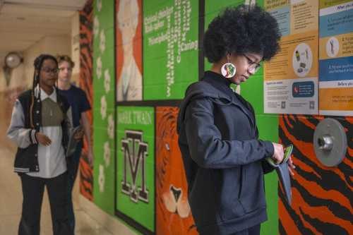 An eighth grader unlocks her cellphone pouch after school followed by other students at Mark Twain Middle School in Alexandria, Virginia, on March 6, 2025.