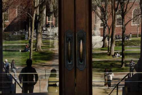 CAMBRIDGE, MASSACHUSETTS - APRIL 17: People are reflected in the doors of the Harry Elkins Widener Memorial Library at Harvard University on April 17, 2025 in Cambridge, Massachusetts.