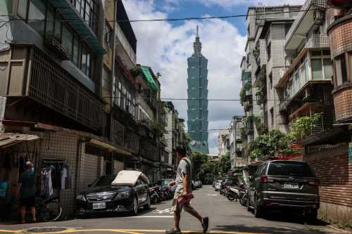 A pedestrian crosses a street as the Taipei 101 skyscraper is seen in the background in Taipei on September 9, 2026.