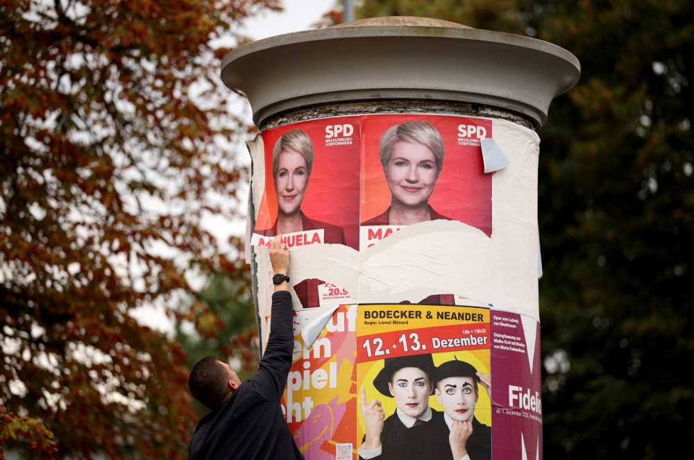 A man removes an election poster of Mecklenburg-Western Pomerania's State Premier and top candidate of the social democratic SPD party Manuela Schwesig in front of the polling station where the candidate of the far-right Alternative for Germany (AfD) is expected to cast his ballot, in accordance with a rule stating that no campaign advertising is permitted in front of polling places on election day, on September 20, 2026 in Schwerin.